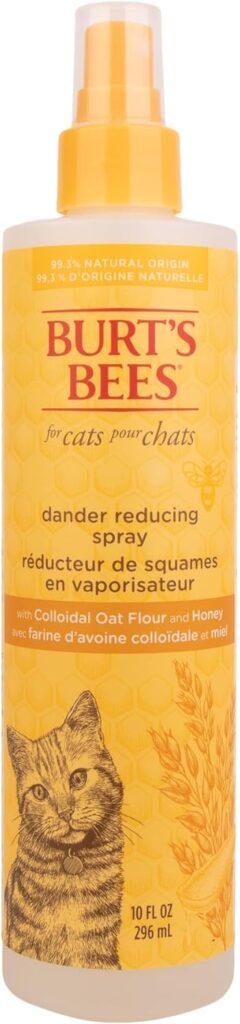 Botella de 296ml (10 fl oz) de spray reductor de caspa para gatos de la marca Burt's Bees. El envase es de color amarillo con un diseño de panal de abeja de fondo y el dibujo de un gato atigrado en la parte inferior. La etiqueta indica que es de origen 99.3% natural y que está formulado con harina de avena coloidal y miel para reducir las escamas y calmar la piel del felino.