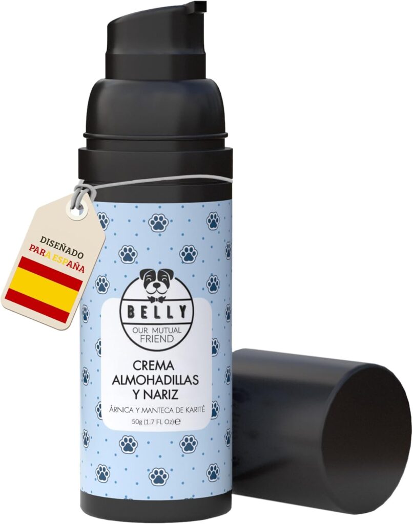 Botella de 50g con dosificador de la crema para almohadillas y nariz de la marca Belly. El envase es negro con una etiqueta azul claro decorada con un patrón de pequeñas huellas oscuras. El texto central indica "CREMA ALMOHADILLAS Y NARIZ" y destaca el uso de árnica y manteca de karité. Incluye una etiqueta colgante con la bandera de España y el texto "DISEÑADO PARA ESPAÑA". Al lado se muestra la tapa protectora negra desmontada.