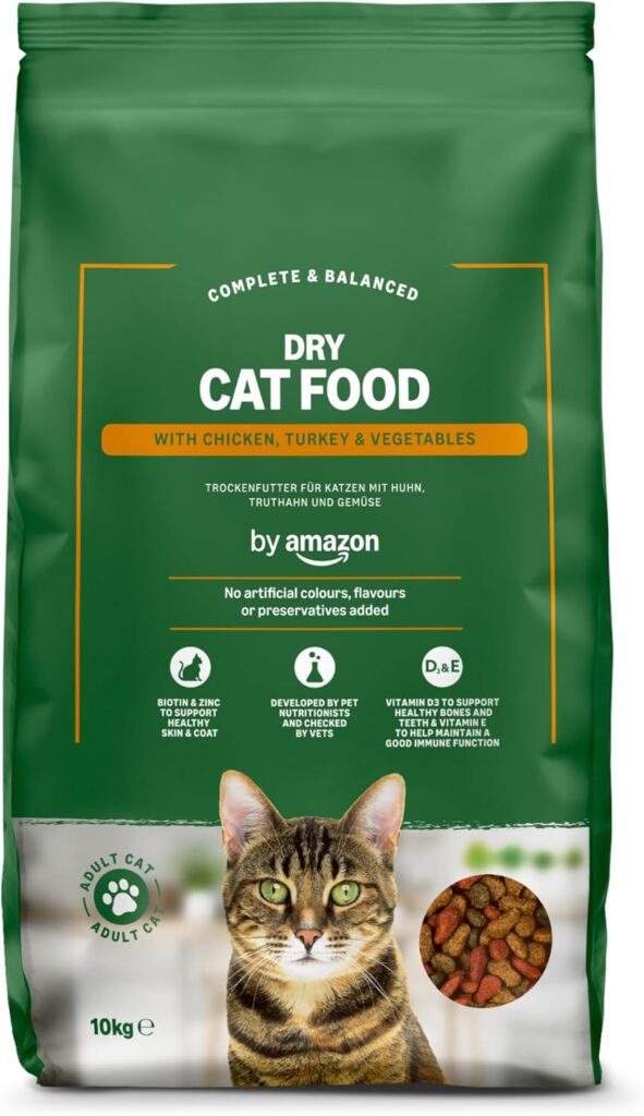 pp1 Saco verde de pienso para gatos adultos ‘by Amazon’, con imagen de un gato atigrado y croquetas. Fórmula completa y equilibrada con pollo, pavo y verduras, sin colorantes ni sabores artificiales, enriquecida con biotina, zinc y vitaminas para piel, pelaje, huesos y sistema inmunitario.