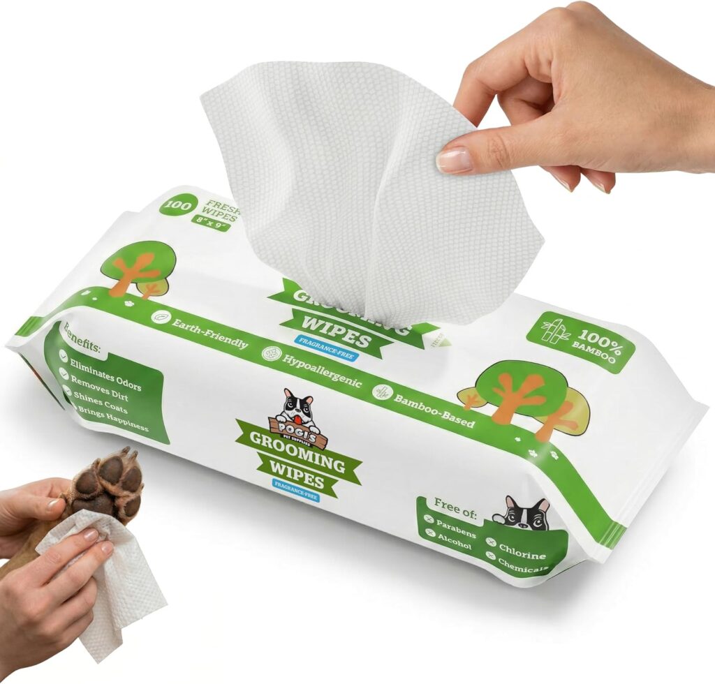 Paquete de 100 toallitas biodegradables para mascotas de la marca Pogi's Grooming Wipes. La imagen muestra una mano extrayendo una toallita blanca con textura de panal del envase. En la esquina inferior izquierda, se ve otra mano limpiando con cuidado la almohadilla de la pata de un perro. El diseño del empaque es blanco y verde, destacando que están hechas de bambú 100%, son hipoalergénicas y no contienen fragancias, alcohol ni parabenos.